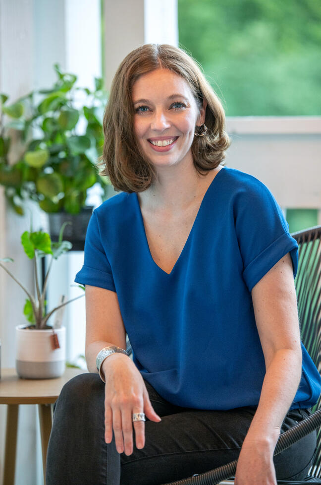 A photo of Megan, content strategist, sitting outside with plants in the background.